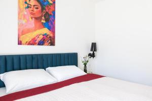 a bedroom with a bed with a painting on the wall at SOFAGOLD Nadštandardný apartmán s veľkou terasou in Košice