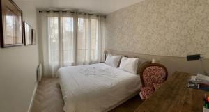 a bedroom with a bed and a table and a window at La fontaine à Chantilly in Chantilly