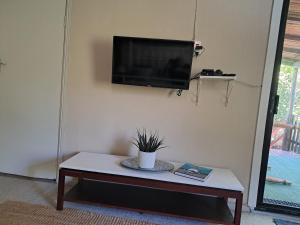 a living room with a table and a tv on a wall at Glen House in Brenton-on-Sea