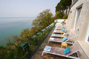 a row of lounge chairs on a balcony overlooking the water at Hotel Riviera & Maximilian's in Trieste