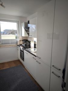 a kitchen with white cabinets and a large window at Schleizauber Ferienwohnung mit Wasserblick und einer großzügigen Terrasse in Schleswig