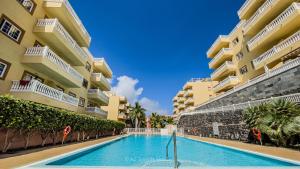a swimming pool in front of some apartment buildings at Primavera apartment with heated pool in Palm-Mar