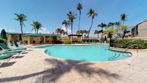 a swimming pool with lounge chairs and palm trees at BV103 - Amazing Oceanfront Condo steps from beach in Humacao