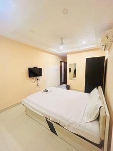 a large white bed in a room with a tv at Newtown Galaxy Guest House in kolkata