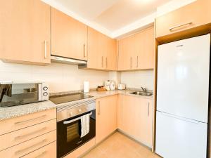 a kitchen with wooden cabinets and a white refrigerator at Apartamento Nautilus by ALÔGA in Fisterra +5 photos