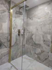 eine Dusche mit einer Glastür und einer Marmorwand in der Unterkunft Zeezicht, volledig gerenoveerd luxe appartement in Middelkerke