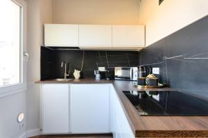 a kitchen with white cabinets and a black wall at NiNNi 12 Apt in Florence +12 photos