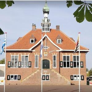 a large brick building with flags in front of it at Herberg de Griffioen in Wolphaartsdijk