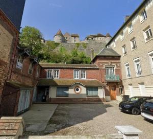 an old brick building with a castle in the background at La Cabine ménage et linge inclus in Dieppe