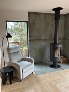 a living room with a chair and a fireplace at Biebrzaski - dom nad Biebrzą in Wierciszewo