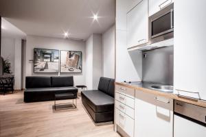 a living room with a couch and a kitchen at Aparthotel Allada 3* in Barcelona