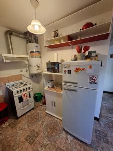 a kitchen with a stove and a white refrigerator at Departamento Naim in Ushuaia +5 photos