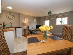 a kitchen and living room with a wooden table with yellow flowers at The Byre in Thirsk