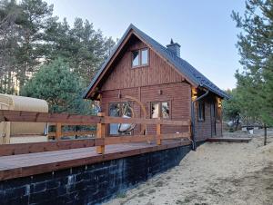 a log cabin with a fence and a porch at Osada Blanka Leśny Zakątek Jezioro Rzeka Swornegacie in Swornegacie 