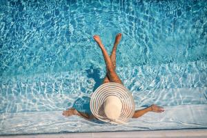 a person in a hat laying in a swimming pool at Borgo Incoronata B&B in Vasto
