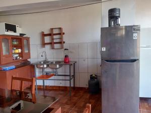 a kitchen with a stainless steel refrigerator in a room at Hostal Aylluq Wasin Casa de Familia-Guest House, habitación Familiar in Urubamba