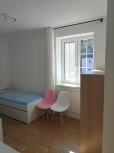 a bedroom with two chairs and a bed and a window at Jeziorna Residence Borne Sulinowo in Borne Sulinowo