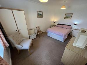 een slaapkamer met een bed en een stoel bij Ellary Cottage in Stonefield