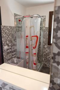 a bathroom with a shower with a red and white shower curtain at Disiu Case Vacanza in Balestrate