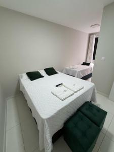 a bedroom with a white bed and a green chair at Casa Arruda Climatizada 2 in Vitória da Conquista