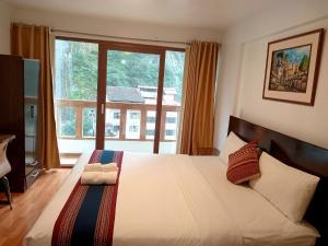a bedroom with a large bed with a large window at El Quetzal MachuPicchu in Machu Picchu