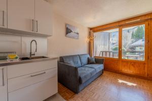 a kitchen with a couch in a kitchen with a window at Résidence Le Prarion 24A ski in- ski out - Happy Rentals in Les Houches