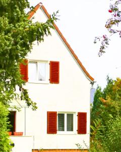 a white house with red shutters on it at O&S Messe city free parking in Munich