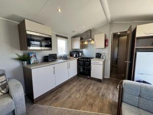 una cucina con mobili bianchi e un forno a piano cottura di Fantasy Island Holiday Park Eastgate - The Seasons with Hot Tub - Coastal Caravan Breaks a Ingoldmells
