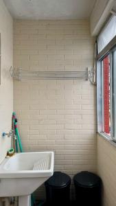 ein Badezimmer mit einem Waschbecken und zwei schwarzen Mülltonnen in der Unterkunft Vista Mar - Kitnet Espaçosa - Tupi in Praia Grande + 22 Fotos