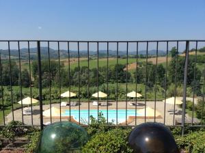 a view of a pool through a fence with umbrellas at Ca' Villa Club Agriturismo in Gabiano