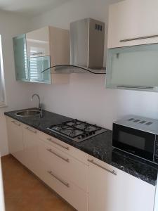 a white kitchen with a stove and a microwave at Apartments Villa Maslinica in Vrboska