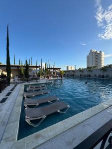 a row of lounge chairs in a swimming pool at Casa Arruda Climatizada 2 in Vitória da Conquista