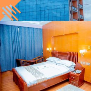 a bedroom with a bed with an orange wall at BWAMI DUBAI HOTEL KASULU in Kasulu