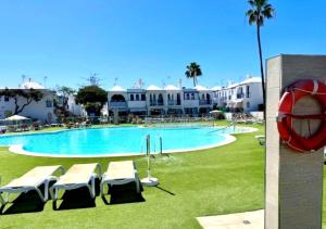 a swimming pool with lounge chairs in front of a resort at Maspalomas J&O in Maspalomas