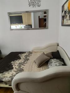 a bed in a room with a mirror and a couch at MakiLen in Vrnjačka Banja
