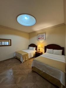 two beds in a room with a blue ceiling at Hotel Plaza Express in Torreón