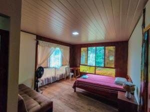 a living room with a bed and a couch and windows at Amisacho in Nueva Loja