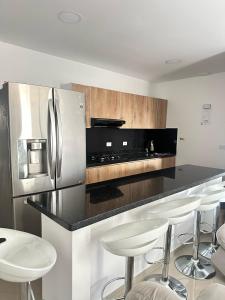 El PeñolにあるLorena Apartamentoのキッチン(ステンレス製の冷蔵庫、スツール付)