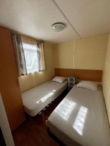 deux lits dans une petite pièce avec une fenêtre dans l'établissement Mobilhome Île d Oléron Camping Les Tamaris, à Saint-Pierre-dʼOléron