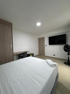 メデジンにあるPraga Room Unicentroのベッドルーム(白い大型ベッド1台、薄型テレビ付)
