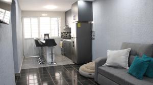 a living room with a couch and a kitchen at Comodo apartamento de 3 habitaciones, a 10 min en vehiculo del Zocalo de Oaxaca in Oaxaca City