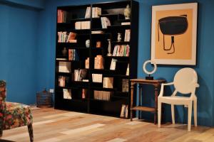 a black book shelf filled with books next to a chair at Happy Inn in Taichung