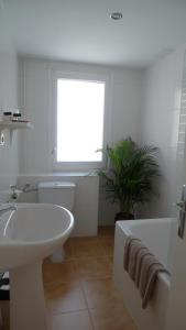 ein weißes Badezimmer mit einer Badewanne, einem Waschbecken und einem Tubermott in der Unterkunft Hotel Peretol in Soldeu