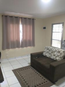 a living room with a brown couch and two windows at Casa completa a 10 min do aeroporto Guarulhos in Guarulhos