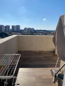 a balcony with a bed and an umbrella on a roof at פנטהאוז 2 חדרים עם נוף משגע ברחובות in Rechovot