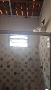 a bathroom with a shower curtain and a window at CASA COLONIAL Ilha da Croa in Barra de Santo Antônio