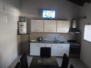 a kitchen with white cabinets and a table and a tv at Adrogué Apart B in Adrogue +8 photos