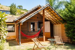 a house with two chairs and a red hammock outside at Pousada Olivier da Montanha - Recanto das Águas in Santo Antônio do Pinhal