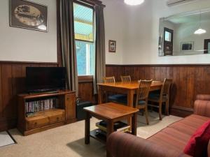 a living room with a table and a television at Creek Cottage in Walhalla