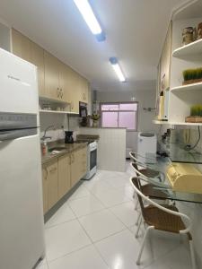 a large kitchen with white appliances and white tile floors at Apartamento aconchegante com varanda! in Teresópolis